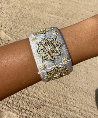 Silver bracelet with gold accents on a wrist against a beige background
